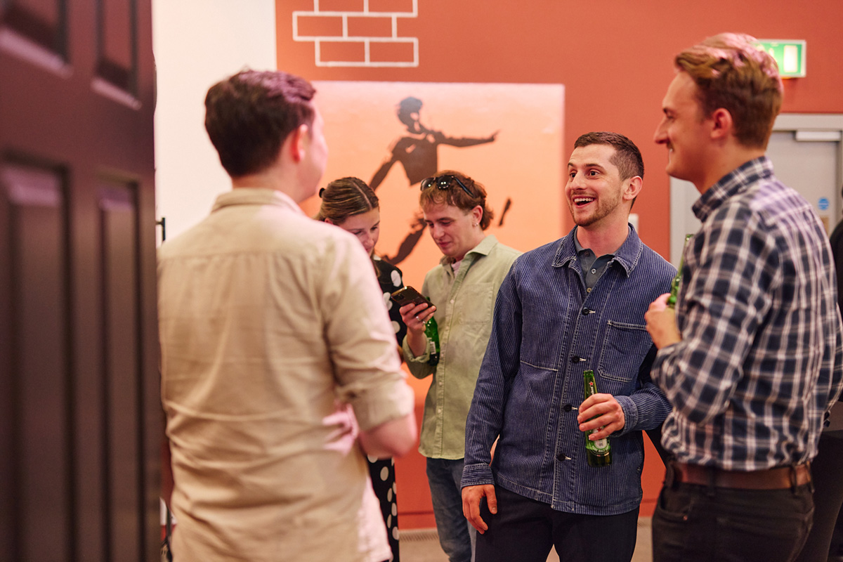 A group of four people drinking and enjoying themselves in the MARKERS exhibition at the National Football Museum.